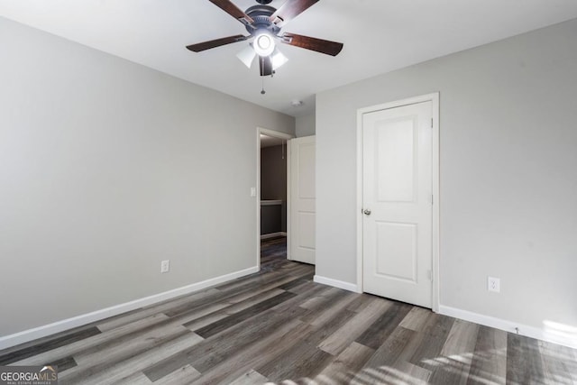 unfurnished bedroom with a ceiling fan, dark wood-style flooring, and baseboards