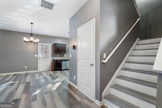 interior space with a notable chandelier, wood finished floors, visible vents, and baseboards