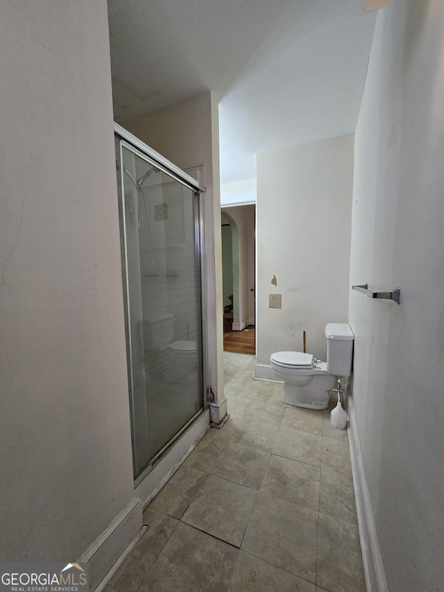 bathroom with toilet and an enclosed shower