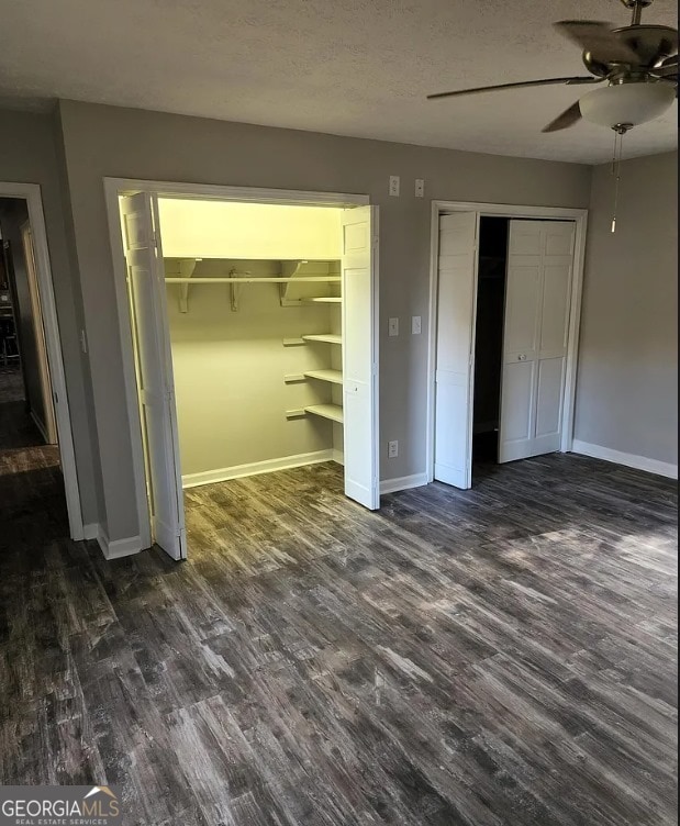 unfurnished bedroom with ceiling fan, dark hardwood / wood-style flooring, and a textured ceiling