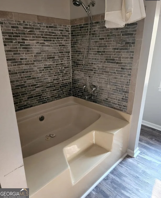 bathroom featuring tiled shower / bath combo and hardwood / wood-style flooring