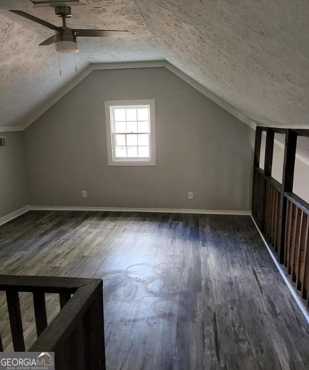 additional living space featuring a textured ceiling, ceiling fan, dark hardwood / wood-style flooring, and lofted ceiling