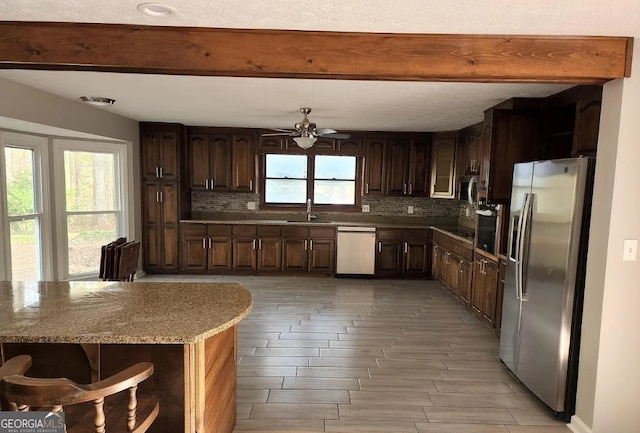 kitchen featuring backsplash, a healthy amount of sunlight, ceiling fan, and stainless steel appliances