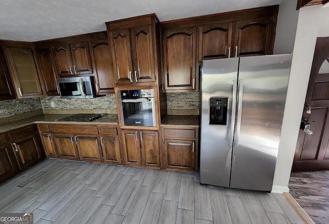 kitchen with light wood-type flooring, tasteful backsplash, and black appliances