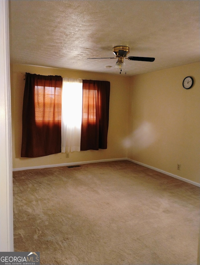 unfurnished room with a textured ceiling, carpet floors, and ceiling fan