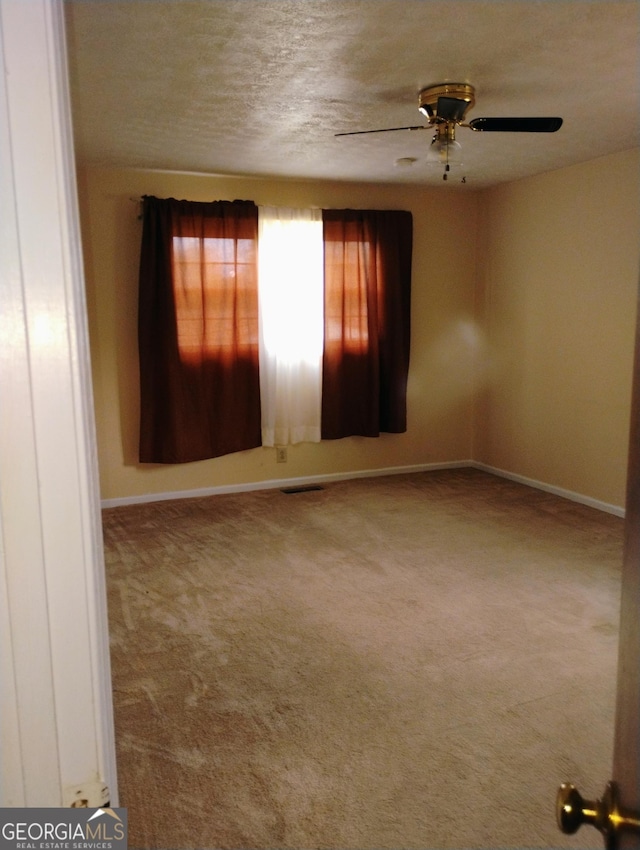 spare room featuring ceiling fan, carpet, and a textured ceiling