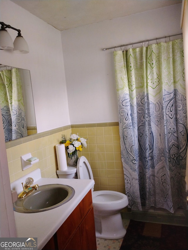 bathroom with walk in shower, vanity, tile walls, and toilet