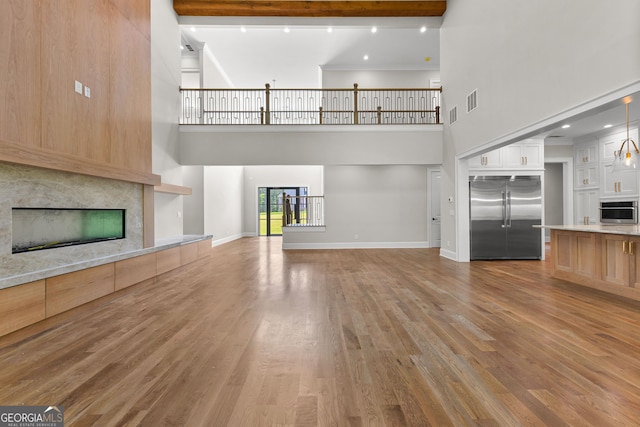 unfurnished living room featuring visible vents, a towering ceiling, wood finished floors, and a fireplace