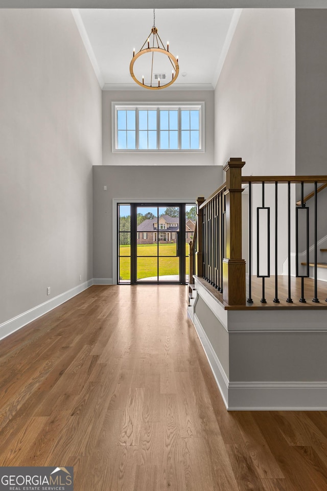 foyer featuring an inviting chandelier, ornamental molding, stairs, and a towering ceiling