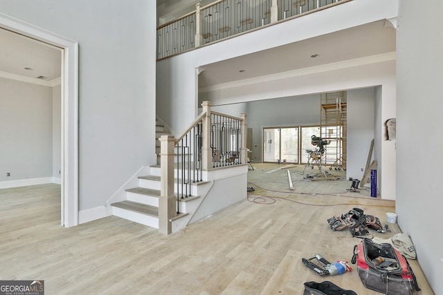 foyer entrance with a towering ceiling, hardwood / wood-style floors, and crown molding