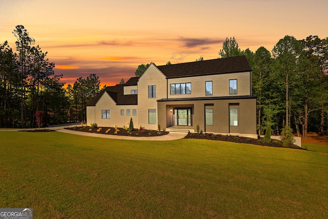 view of front of home featuring stucco siding and a yard