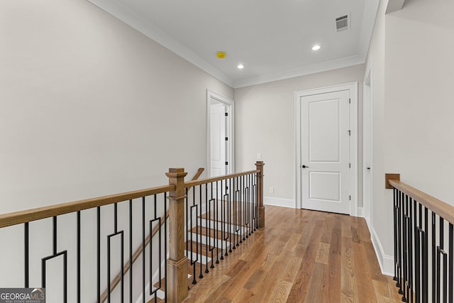 hallway with visible vents, wood finished floors, baseboards, recessed lighting, and an upstairs landing