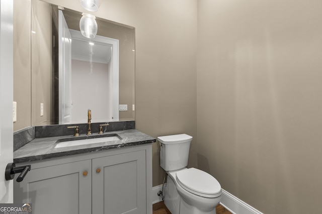 half bath with vanity, crown molding, and toilet