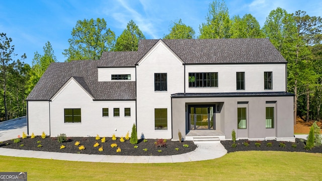 modern inspired farmhouse with a shingled roof and a front yard