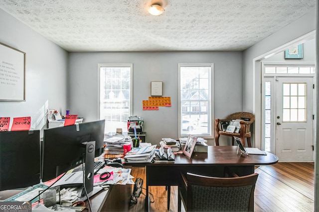 home office featuring plenty of natural light, wood-type flooring, and a textured ceiling