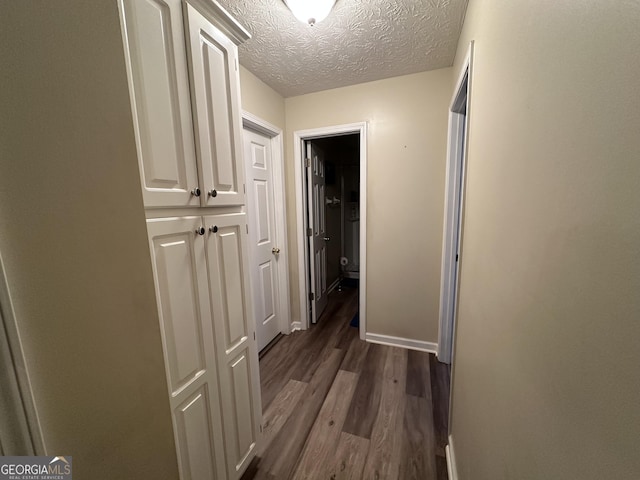 corridor with hardwood / wood-style floors and a textured ceiling