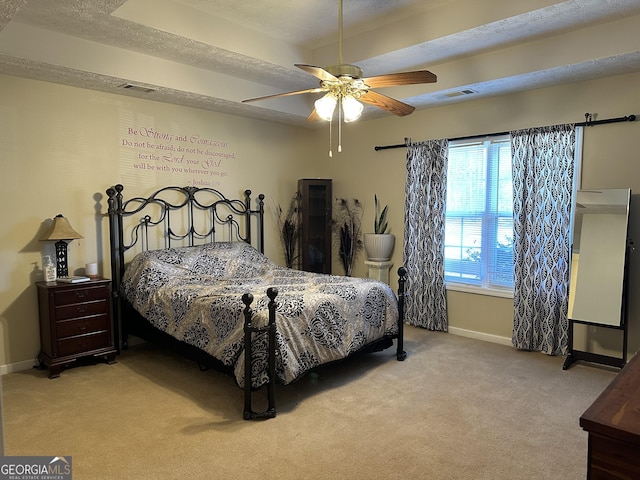 bedroom featuring ceiling fan, light colored carpet, and a textured ceiling