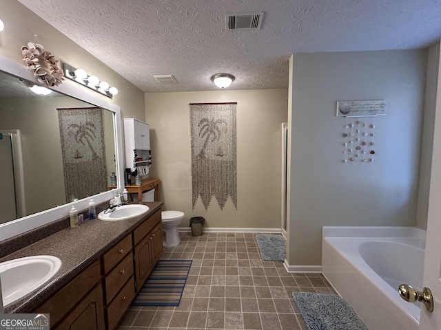 bathroom with a washtub, vanity, a textured ceiling, and toilet