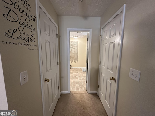 corridor featuring a textured ceiling and light colored carpet