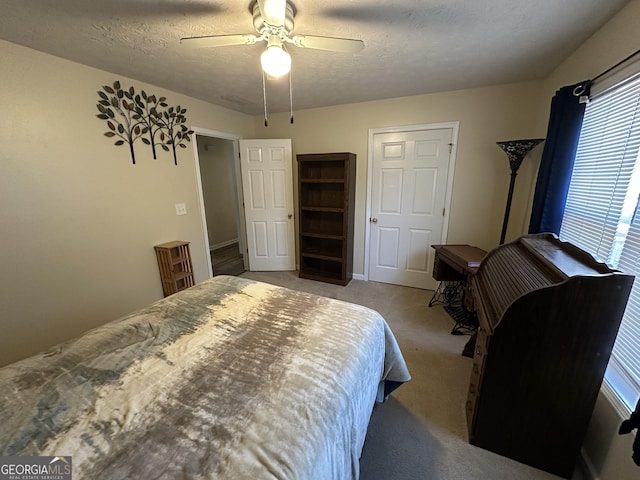 bedroom with a textured ceiling, light colored carpet, multiple windows, and ceiling fan