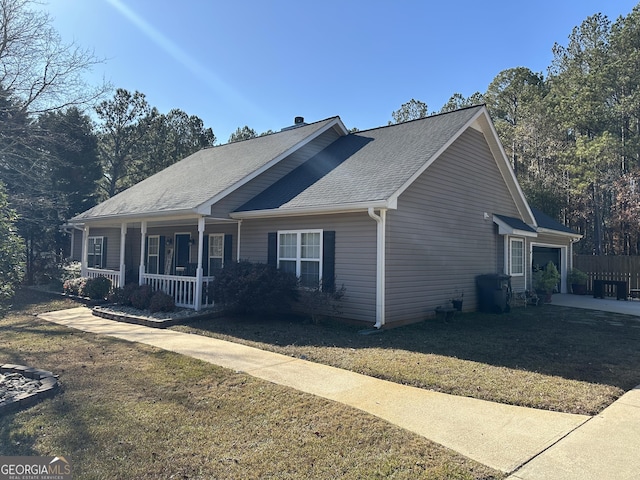 view of front of home with covered porch, a garage, and a front lawn