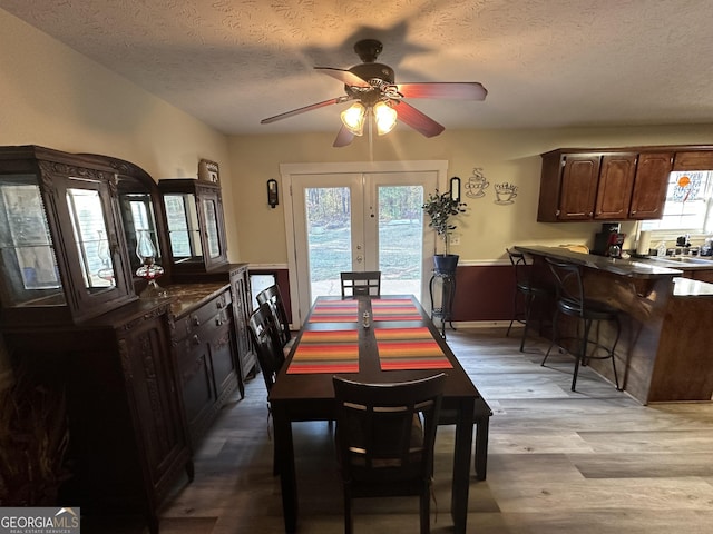 dining room featuring ceiling fan, french doors, a textured ceiling, and light hardwood / wood-style flooring