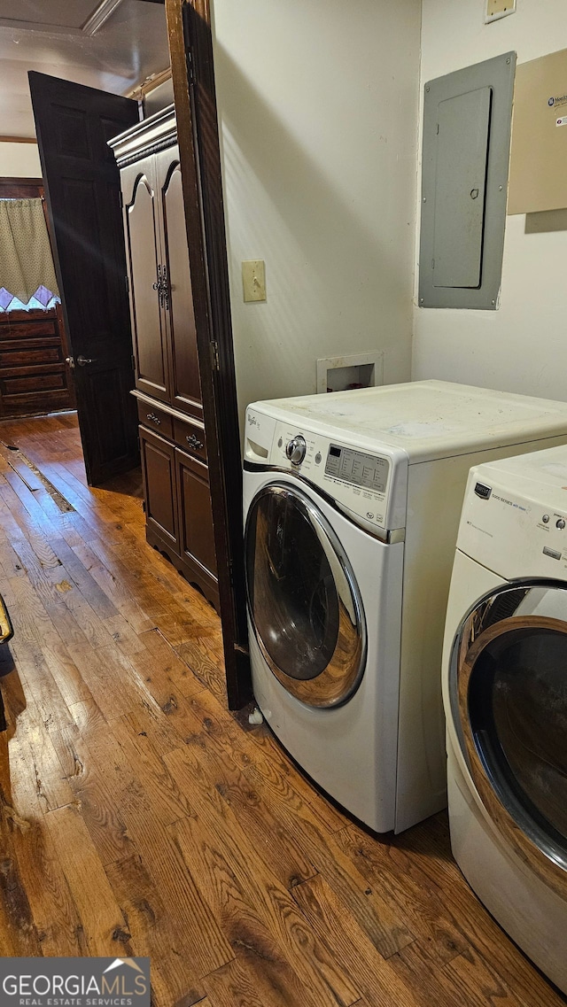 clothes washing area featuring dark hardwood / wood-style flooring, electric panel, and washer and dryer