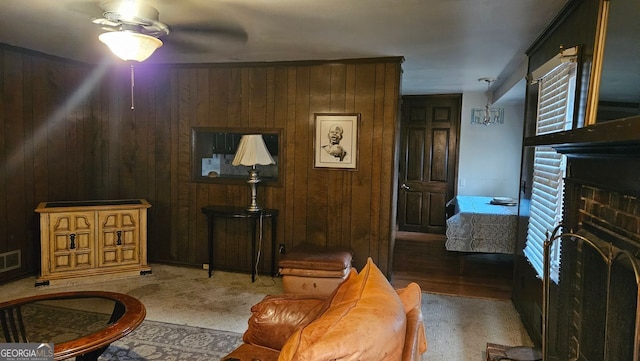 living room with ceiling fan, a fireplace, and wooden walls