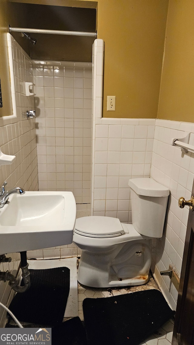 bathroom featuring tile walls, sink, toilet, and tiled shower