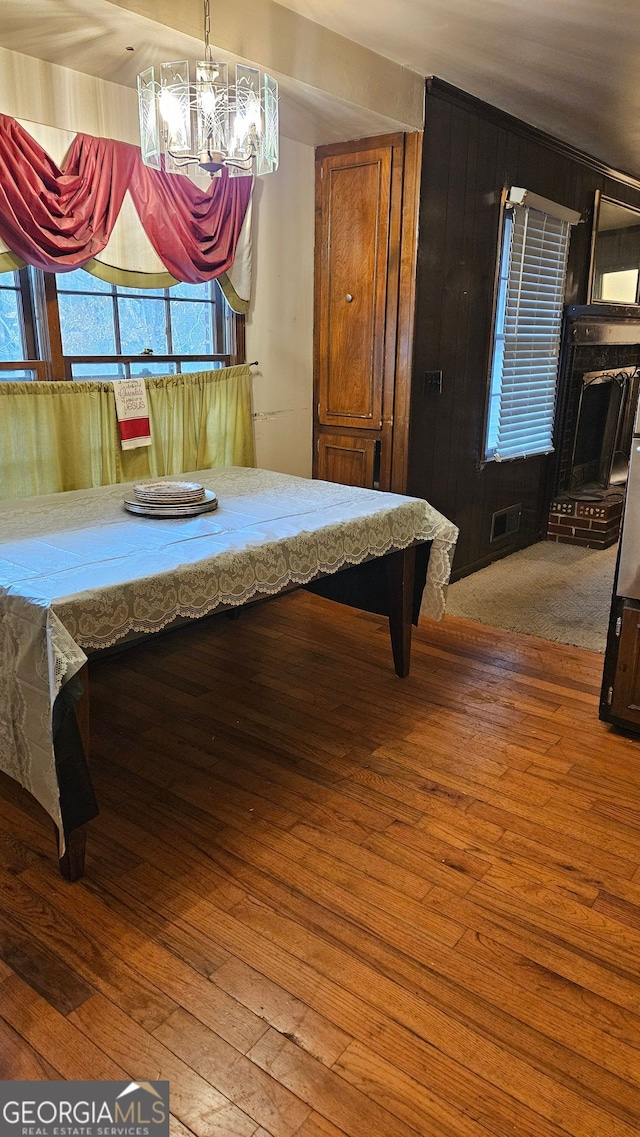 dining room with an inviting chandelier, wooden walls, and hardwood / wood-style flooring