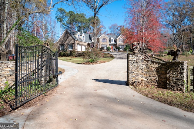 view of street with driveway, a gated entry, and a gate