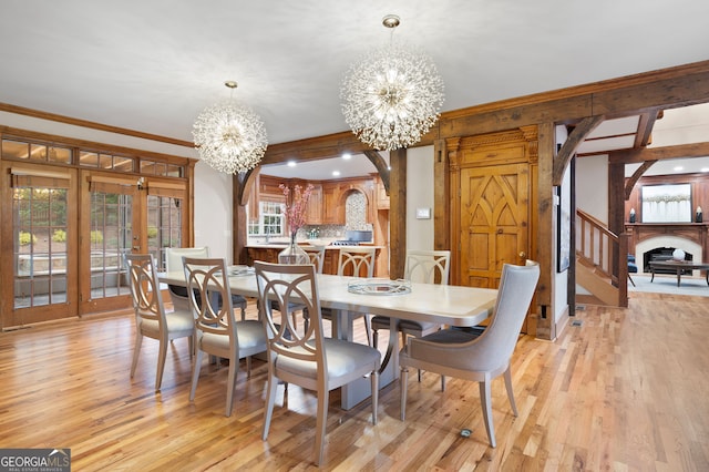 dining area featuring a chandelier, french doors, light hardwood / wood-style flooring, and crown molding