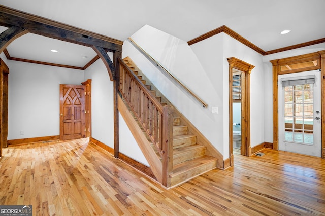 stairs with hardwood / wood-style floors and ornamental molding