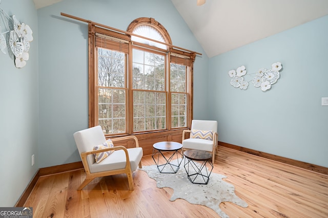 living area with light hardwood / wood-style flooring, a healthy amount of sunlight, and lofted ceiling