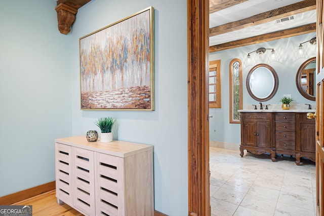 hallway featuring sink and beamed ceiling