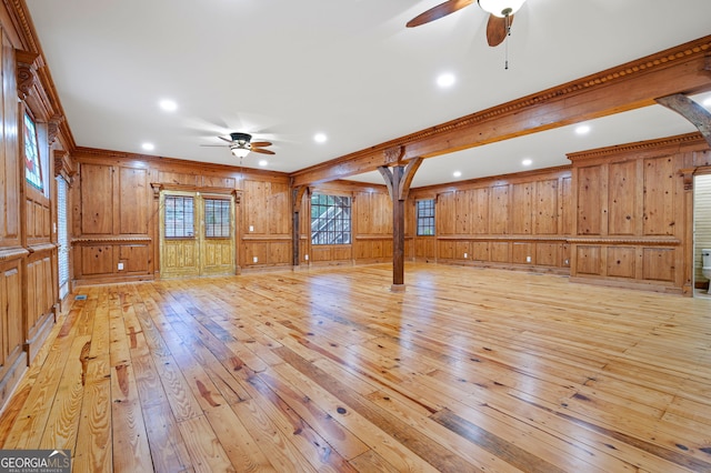 interior space featuring ceiling fan, light wood-type flooring, and wooden walls