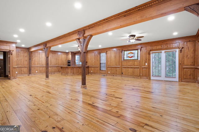 unfurnished living room with wood walls, light hardwood / wood-style flooring, and crown molding