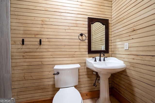 bathroom with toilet and wood walls