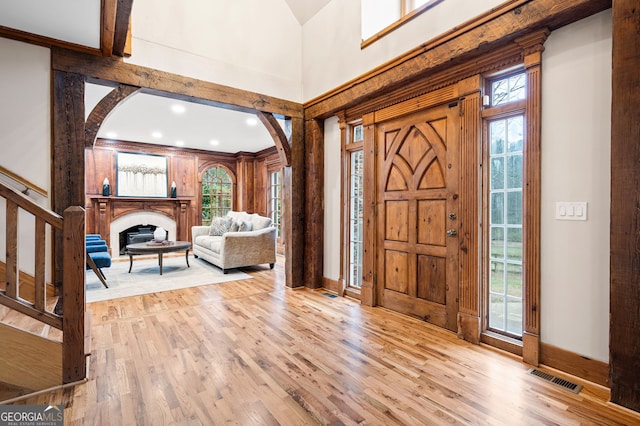 foyer entrance with light wood-type flooring, plenty of natural light, and crown molding