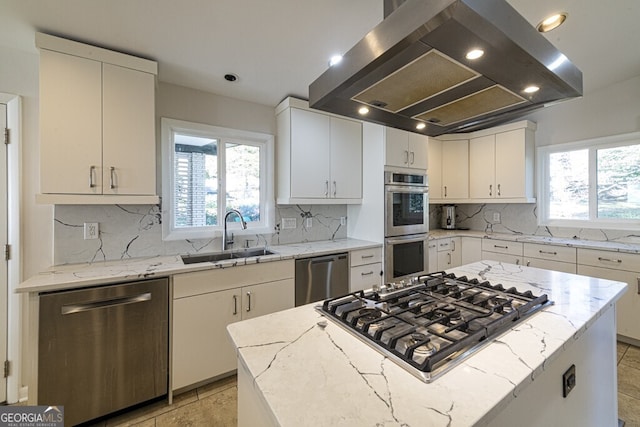 kitchen with sink, a kitchen island, light stone counters, island exhaust hood, and stainless steel appliances