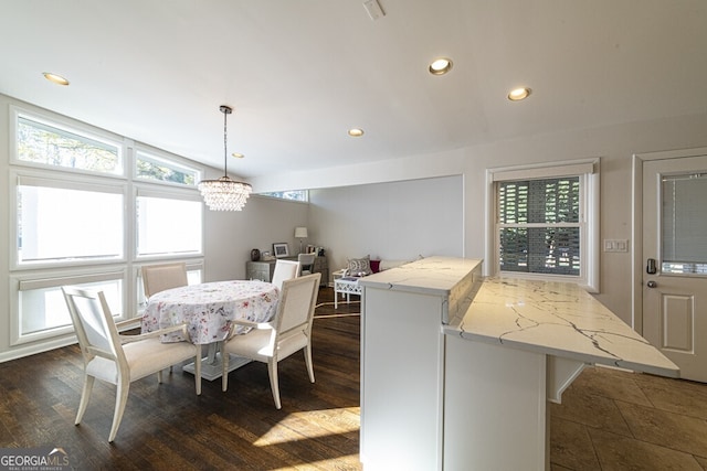 dining space featuring dark hardwood / wood-style flooring, vaulted ceiling, and an inviting chandelier