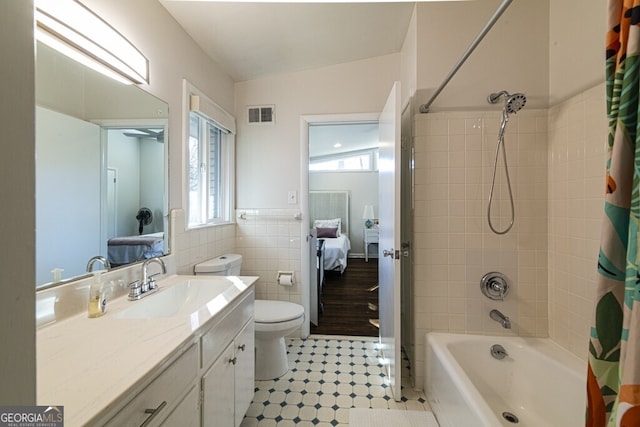 full bathroom featuring vanity, shower / bathtub combination with curtain, tile walls, toilet, and lofted ceiling