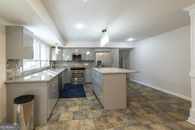 kitchen featuring backsplash, gray cabinetry, stainless steel appliances, sink, and a center island