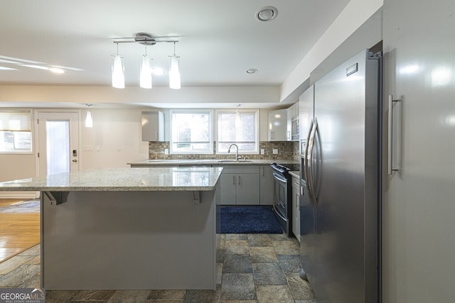 kitchen featuring pendant lighting, decorative backsplash, sink, and appliances with stainless steel finishes