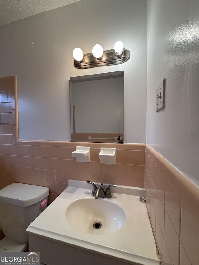 bathroom with vanity, toilet, tile walls, and a textured ceiling