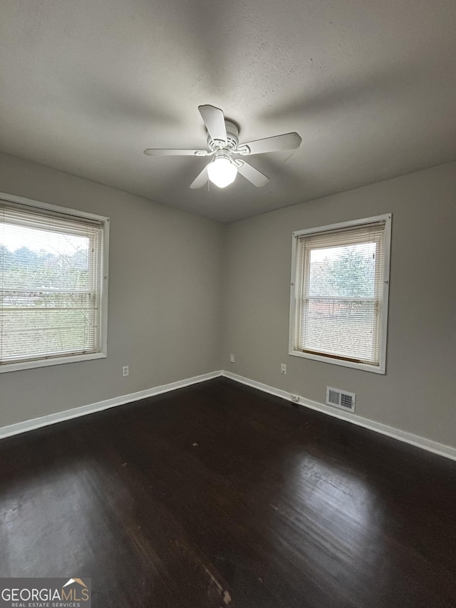 unfurnished room featuring dark wood-type flooring, a wealth of natural light, and ceiling fan