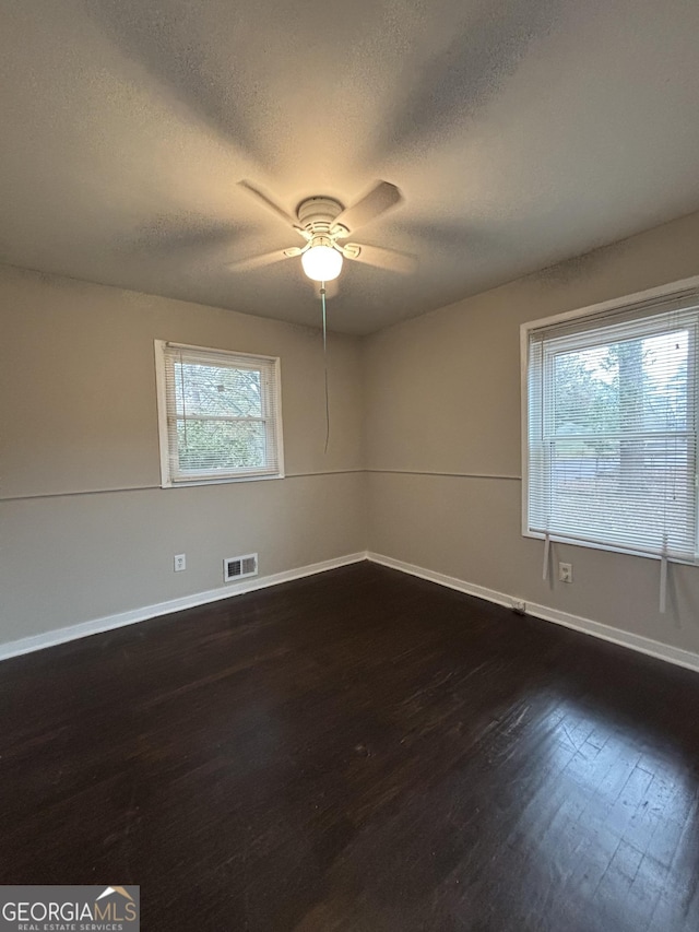 unfurnished room featuring dark wood-type flooring, ceiling fan, and a textured ceiling