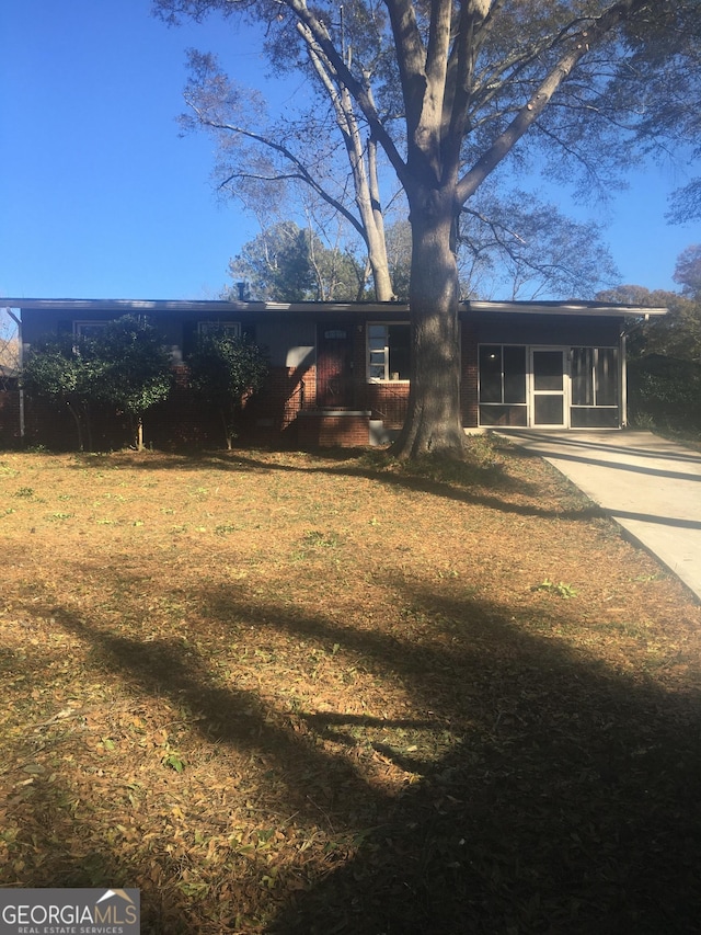 rear view of property with a sunroom and a lawn