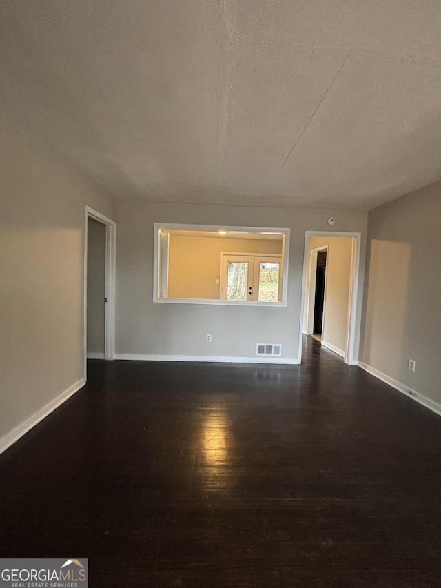 empty room with dark wood-type flooring and a textured ceiling