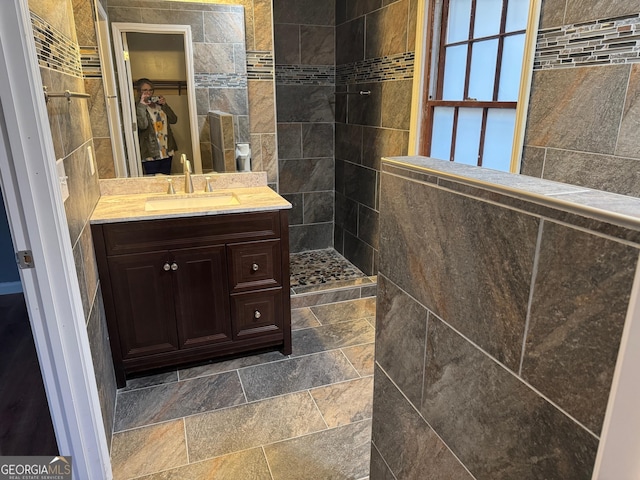 bathroom with a tile shower and vanity